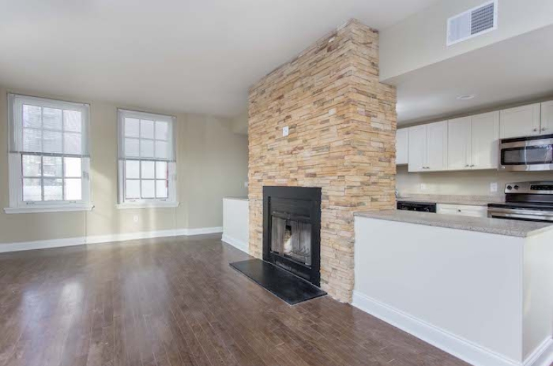 A stunning fireplace with stone surround column adjoins the kitchen and dining space