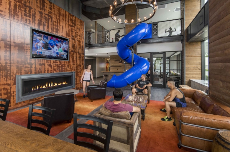 Lounge features television, seating, and slide next to the gym
