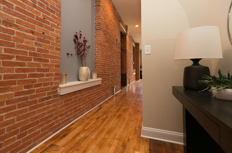 Hallway featuring brick wall and recessed lighting