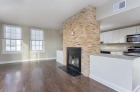 A stunning fireplace with stone surround column adjoins the kitchen and dining space