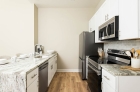 A kitchen aisle with a sink across from the cabinets, a refrigerator, a stove, and a microwave