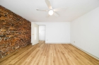 Bedroom featuring hardwood and exposed brick walls 